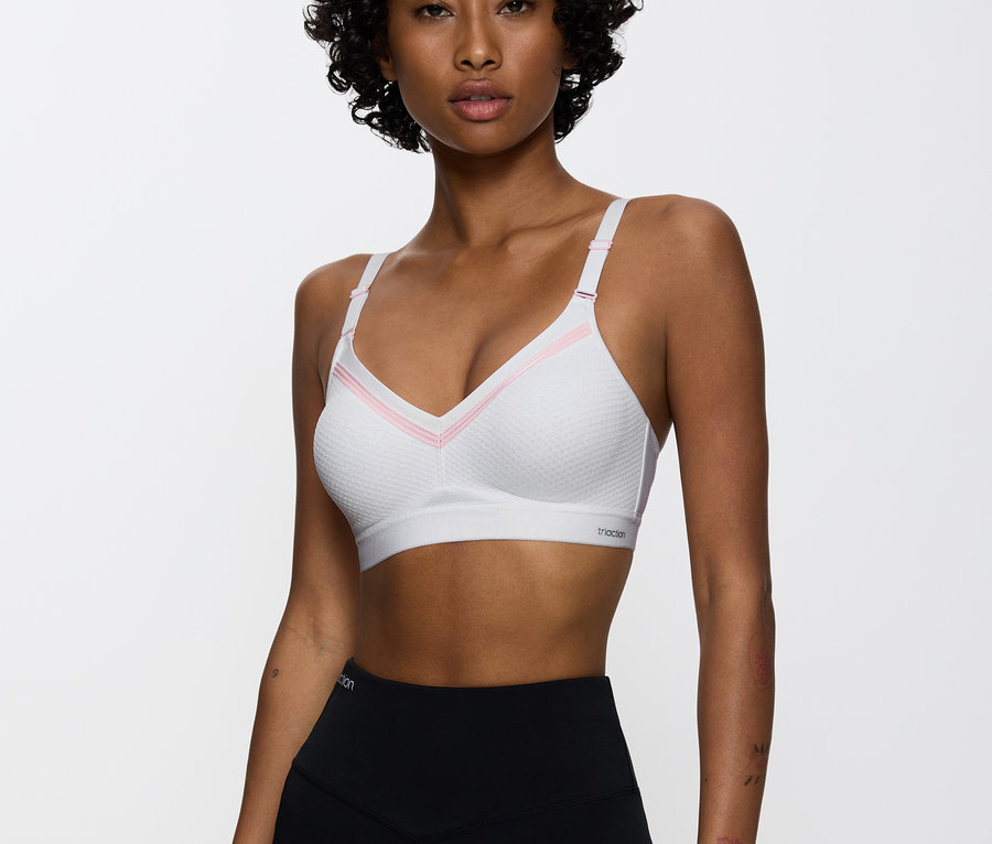 Frau trägt einen weißen Sport-BH mit rosa Details und schwarze Leggings.
