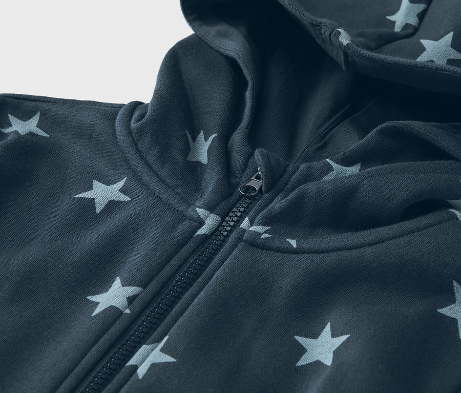 Nahaufnahme eines marineblauen Kapuzenpullovers mit Sternenmuster und Reißverschluss.