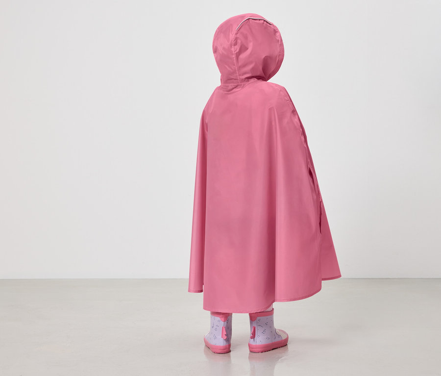 Rückansicht eines Kindes mit rosa Regenponcho mit Kapuze und lila Gummistiefeln mit Muster vor einem weißen Hintergrund.