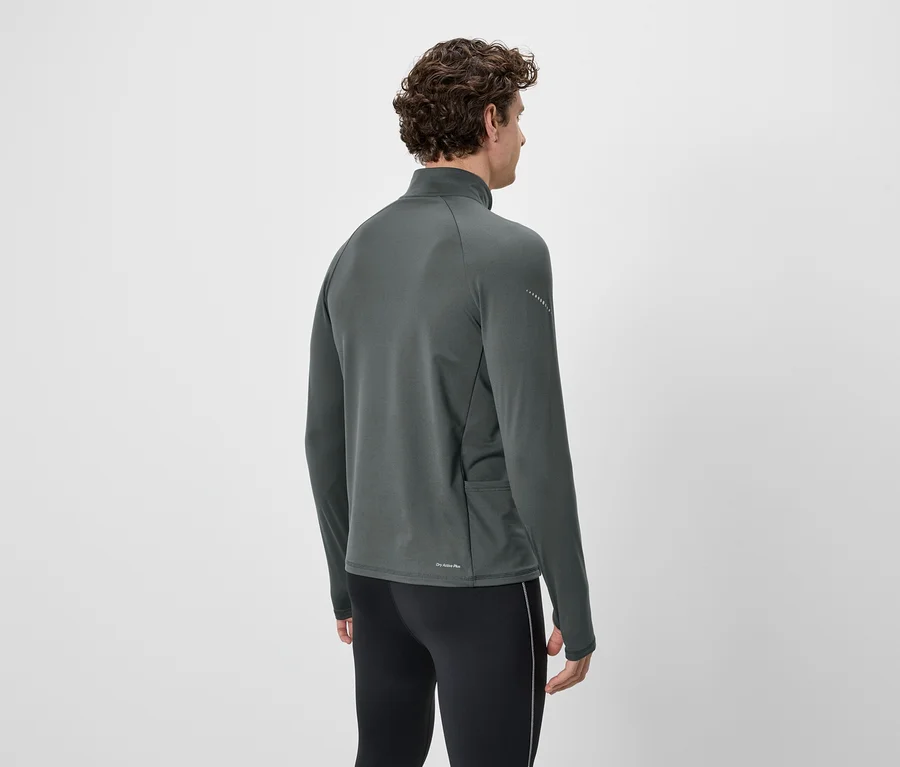 Mann von hinten, mit lockigen Haaren, trägt ein graues Langarmshirt und schwarze Leggings.