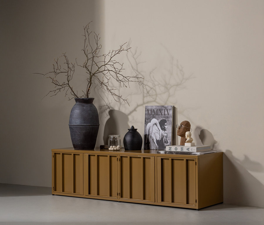 Auf einem honiggelben WOOOD Metall-TV-Schrank »Level« stehen eine Vase mit Ästen, Deko-Objekte und Bücher.