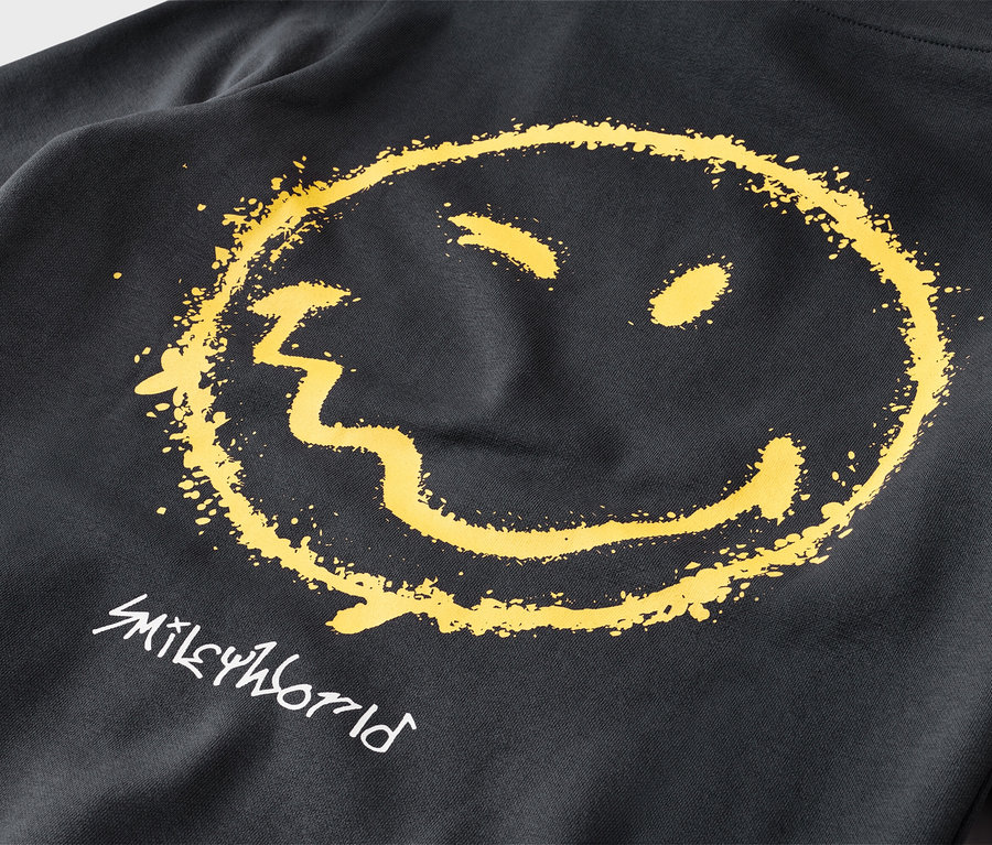 Nahaufnahme eines schwarzen Sweatshirts mit einem großen, gelben, verwaschenen Smiley-Gesicht und dem weißen Schriftzug „SMILEYWORLD“ darunter.