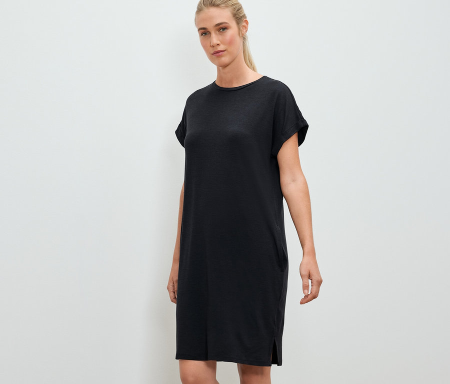 Frau posiert in einem schwarzen Outdoor-Kleid.