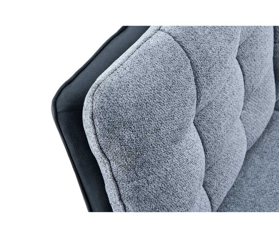 Nahaufnahme einer hellgrauen, getufteten Stoffpolsterung eines Stuhls oder Sofas mit dunklem, glattem Material dahinter.
