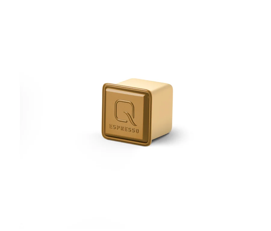 Eine einzelne, hellgoldene, quadratische Qbo Espresso Kapsel mit einem dunkleren goldenen Deckel, der ein 'Q'-Logo und den Schriftzug 'ESPRESSO' zeigt.