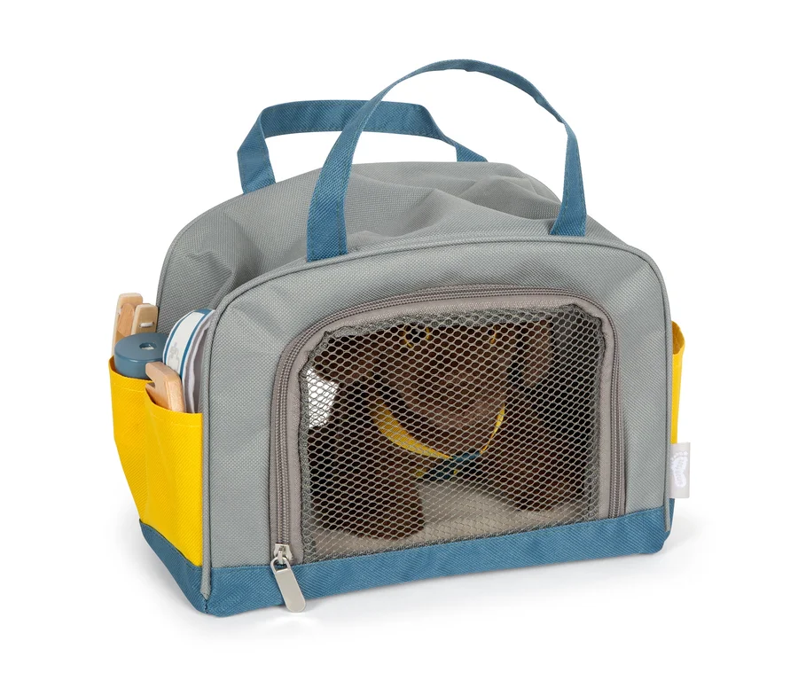 Ein brauner Plüschhund in einer grauen small foot Tasche mit blauen Akzenten und gelber Tasche.