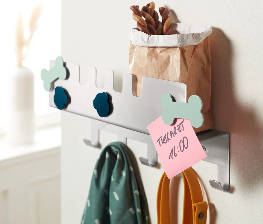Eine Tier-Garderobe hängt an der Wand. An der Garderobe hängen eine Leine, ein Halstuch und eine Papiertüte.