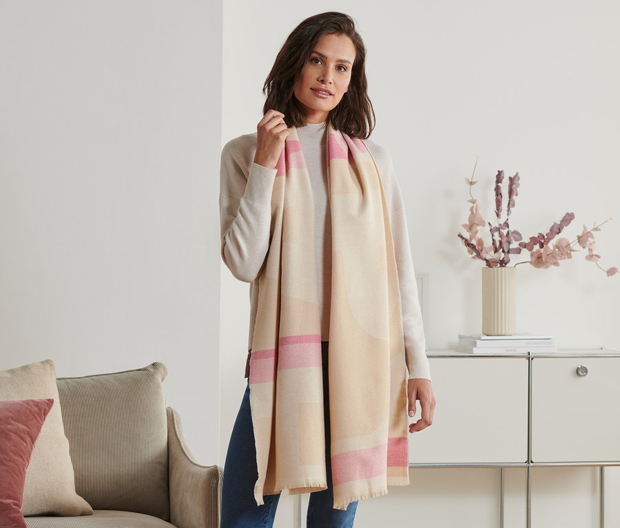 Frau posiert mit beigem und pinkem Schal mit Fransen.