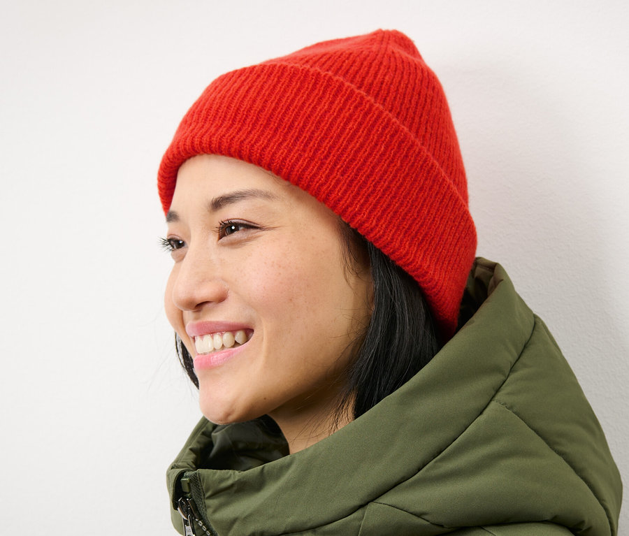 Lächelnde Frau mit orangefarbener Strickmütze.