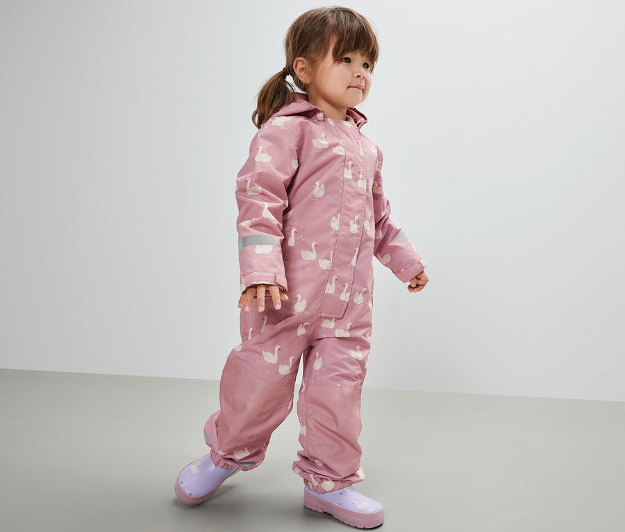 Mädchen trägt einen Kinder-Regen-Einteiler, Schwan. Sie trägt dazu lila Gummistiefel.