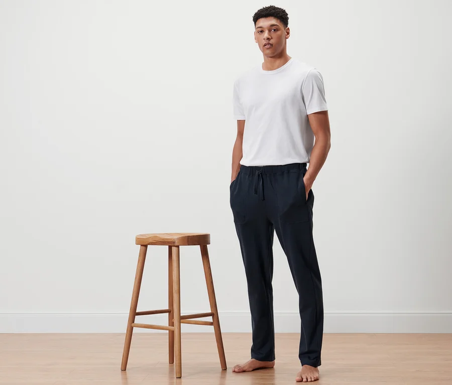 Mann steht neben einem Holzhocker und trägt eine dunkelblaue Homewearhose.