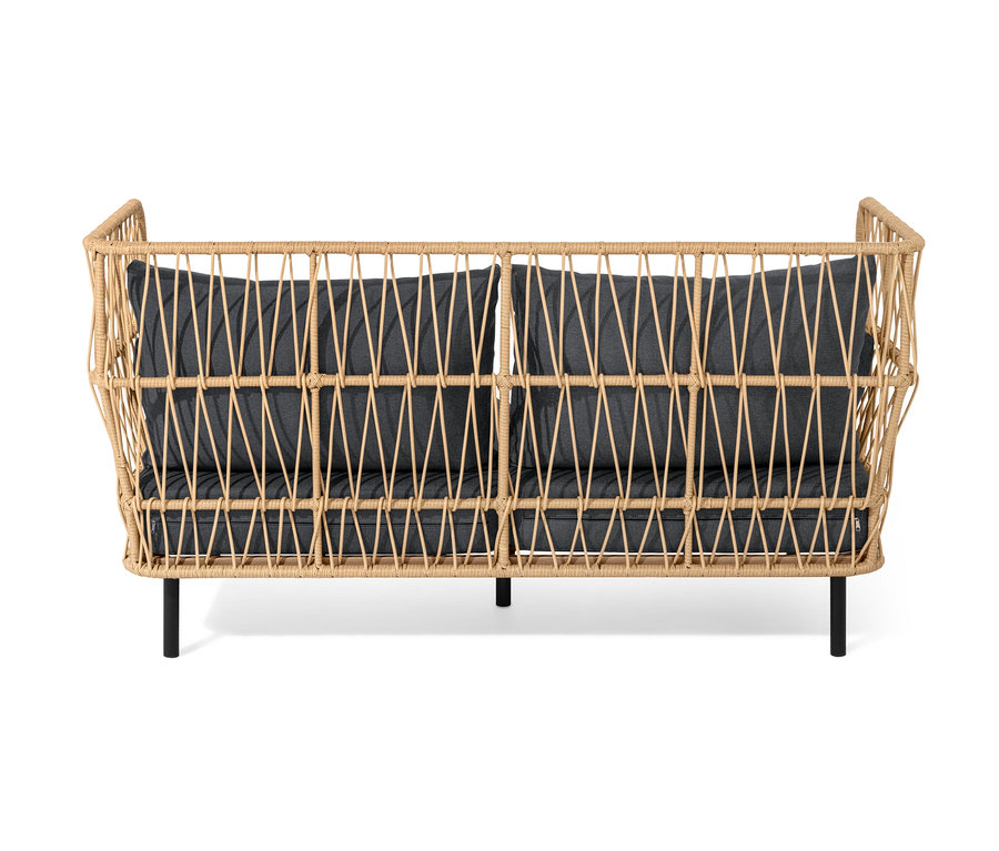 Ein Loungesofa mit Fußhocker und dunkelgrauen Kissen.