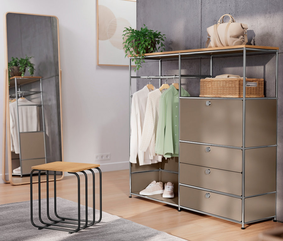 Im Raum stehen eine taupefarbene Metallkommode »CN3« mit Holzplatte, Kleiderstange, Klappenfach und drei Schubladen, sowie ein Hocker und ein Spiegel.