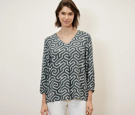 Frau trägt eine Bluse in Crinkle-Optik und weiße Hose.