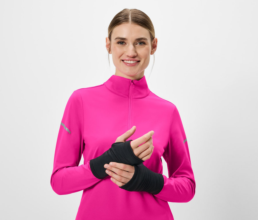 Lächelnde Frau trägt ein pinkfarbenes Langarmshirt und schwarze Armstulpen.