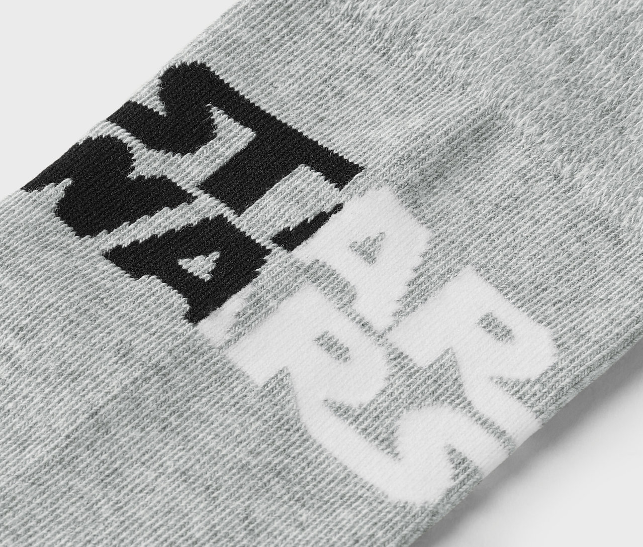 Detailaufnahme einer grauen Socke mit schwarzer und weisser Beschriftung.