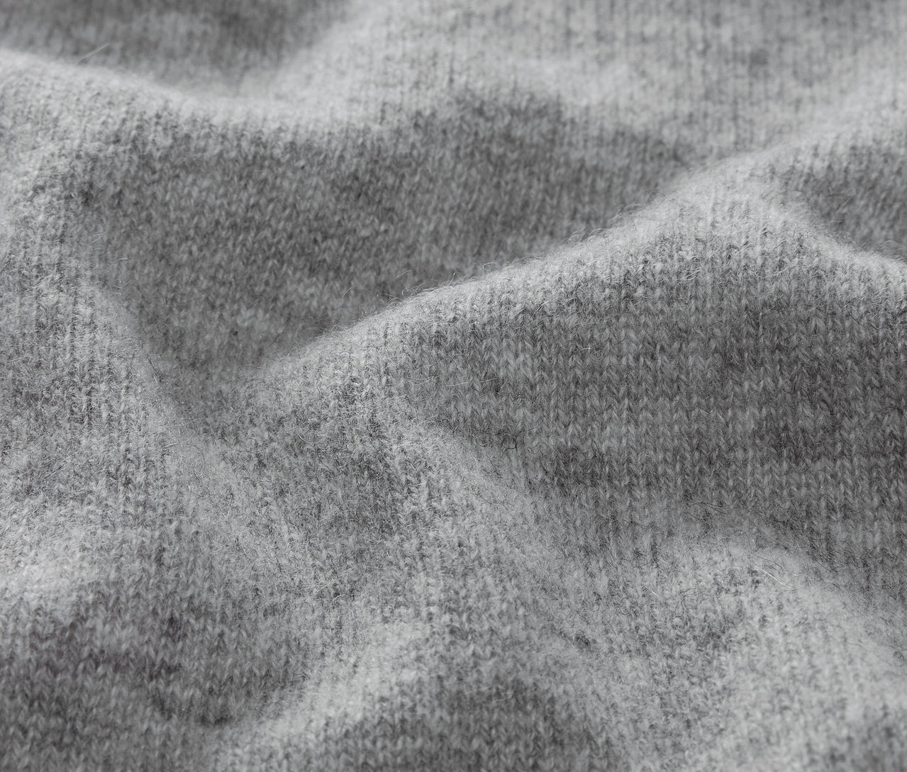 Nahaufnahme der Textur eines grauen Strickstoffs.