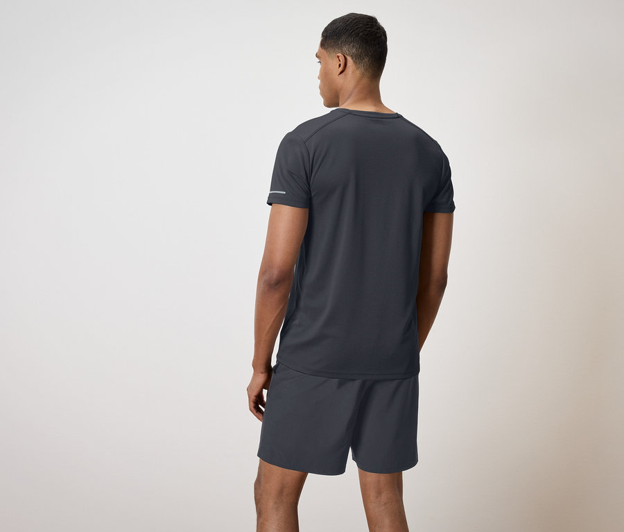 Ein Mann in schwarzem T-Shirt und Shorts steht mit dem Rücken zum Betrachter.