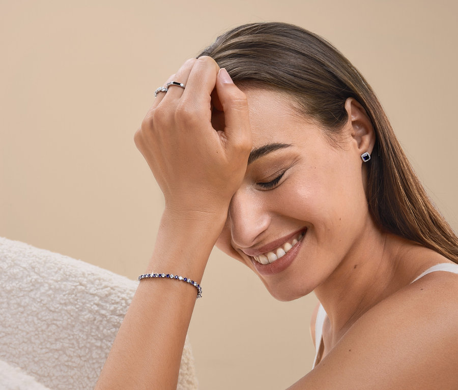 Lächelnde Frau mit Ring, Armband und Ohrringen.