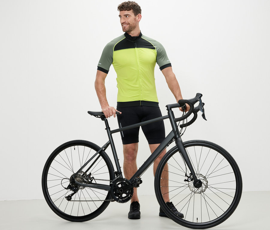 Mann steht neben einem Fahrrad und trägt ein gelbes Fahrrad-Trikot.