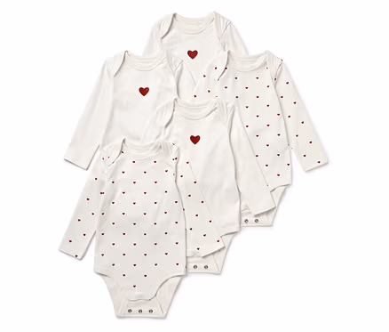 Fünf weiße Baby-Langarmbodys, einige mit einem roten Herz in der Mitte, andere mit einem roten Herzmuster.