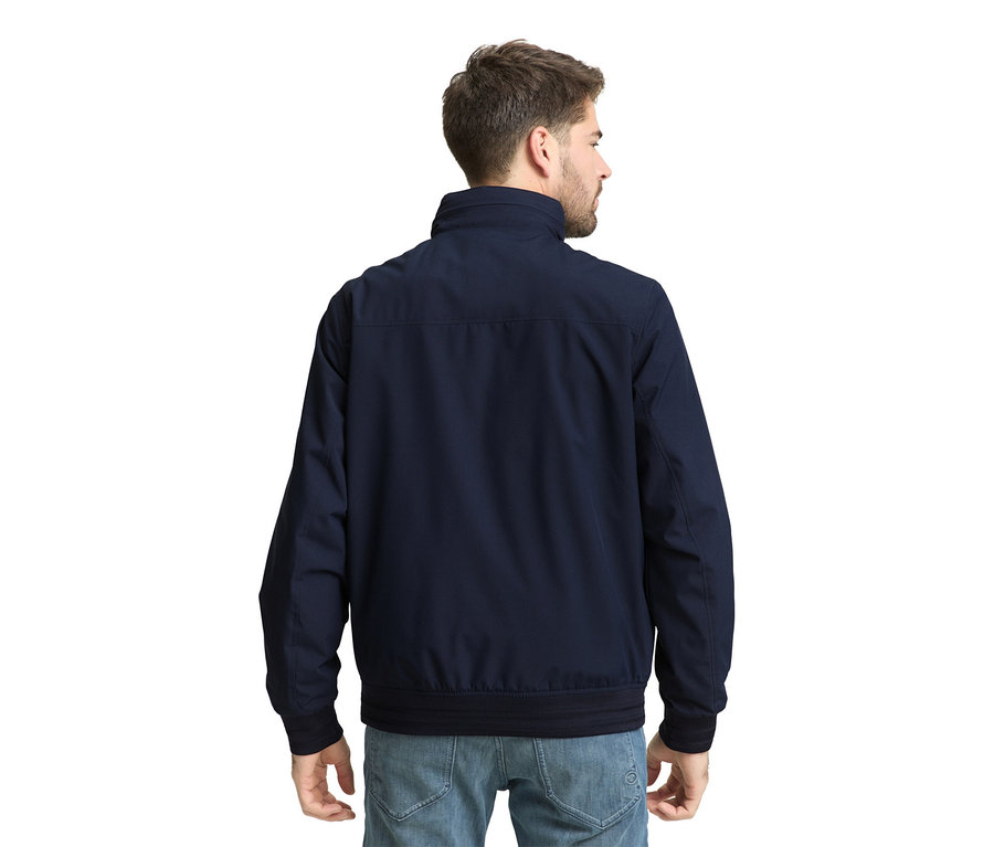 Ein Mann von hinten, der eine dunkelblaue Tom Tailor Blouson-Jacke und Jeans trägt.