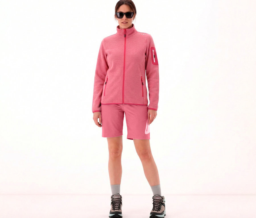 Frau mit Sonnenbrille trägt CMP Damen-Knit-Tech-Fleece, magenta-weiß, Shorts, Socken und Wanderschuhe vor einem weißen Hintergrund.