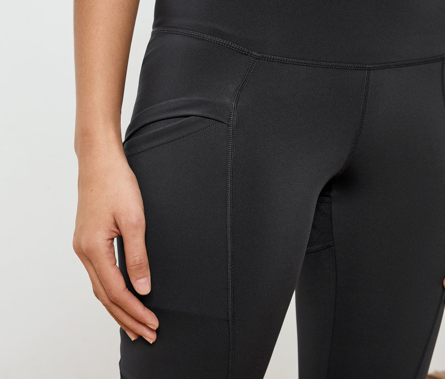 Nahaufnahme einer Frau, die schwarze Leggings mit einer Tasche trägt.