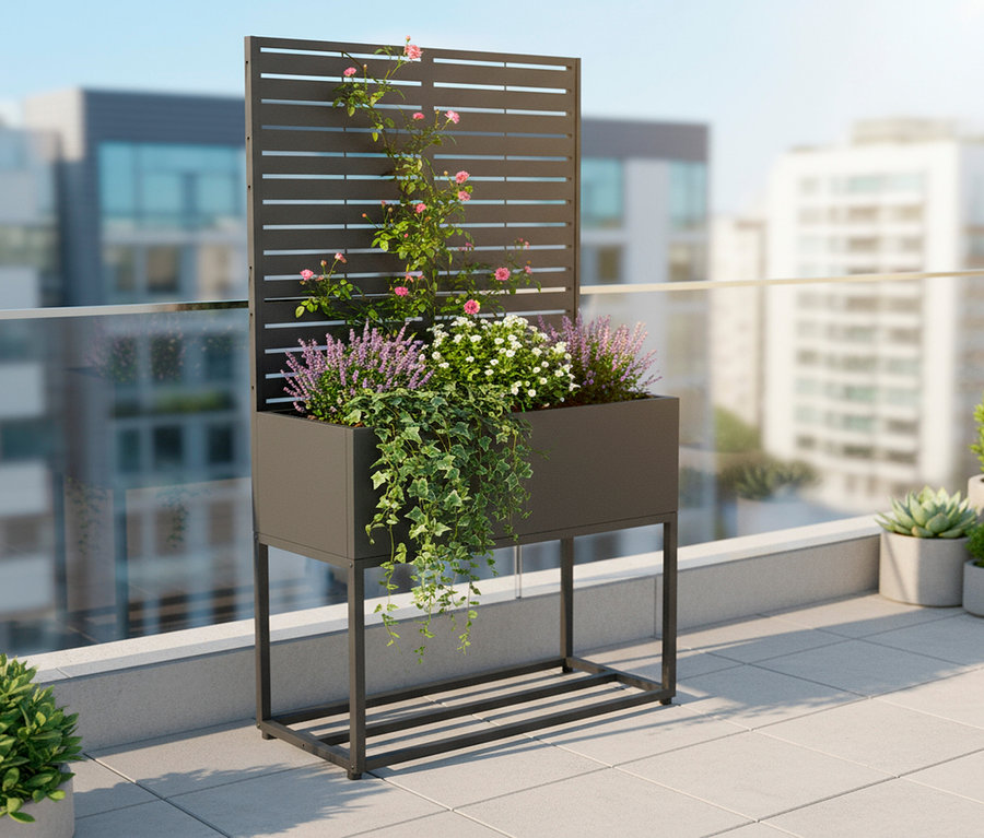 Aufnahme eines grauen, erhöhten Pflanzgefäßes mit Spalier auf einem Balkon, bepflanzt mit verschiedenen Blumen und Pflanzen.