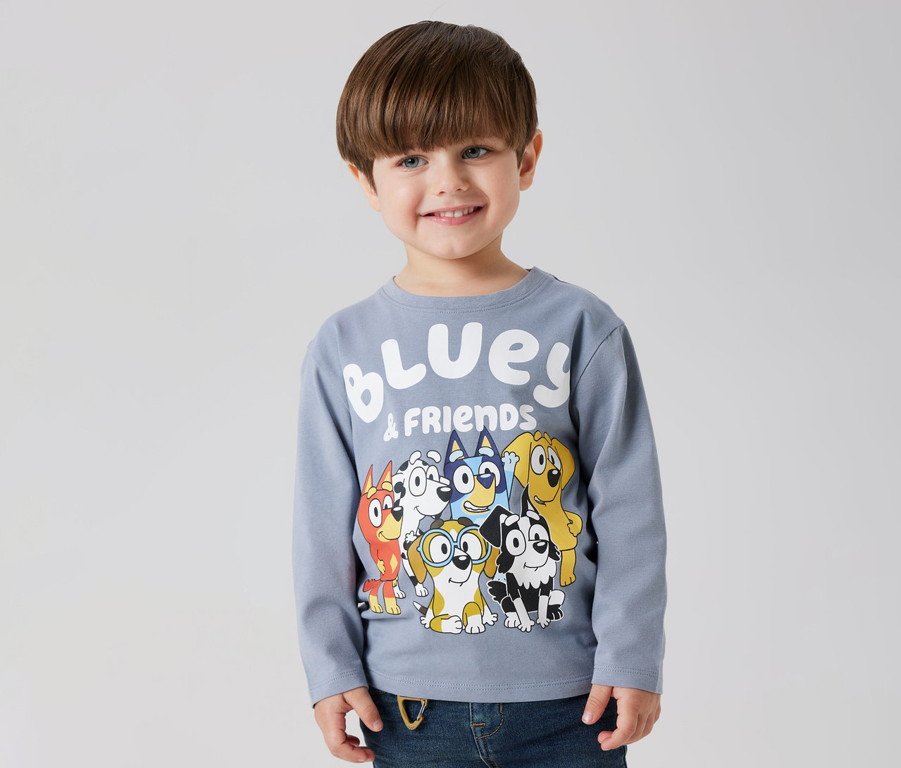 Lächelnder Junge trägt ein NAME IT Kinder-Langarmshirt »BLUEY« mit Bluey- und Freunde-Motiv.