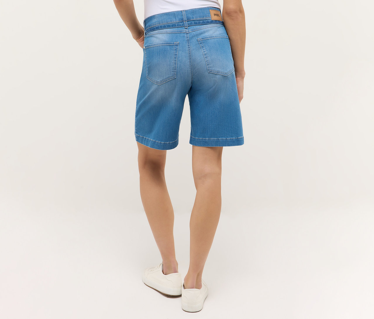 Rückansicht einer Frau in hellblauen Angels Denim »Lia City« Shorts und weißen Schuhen.