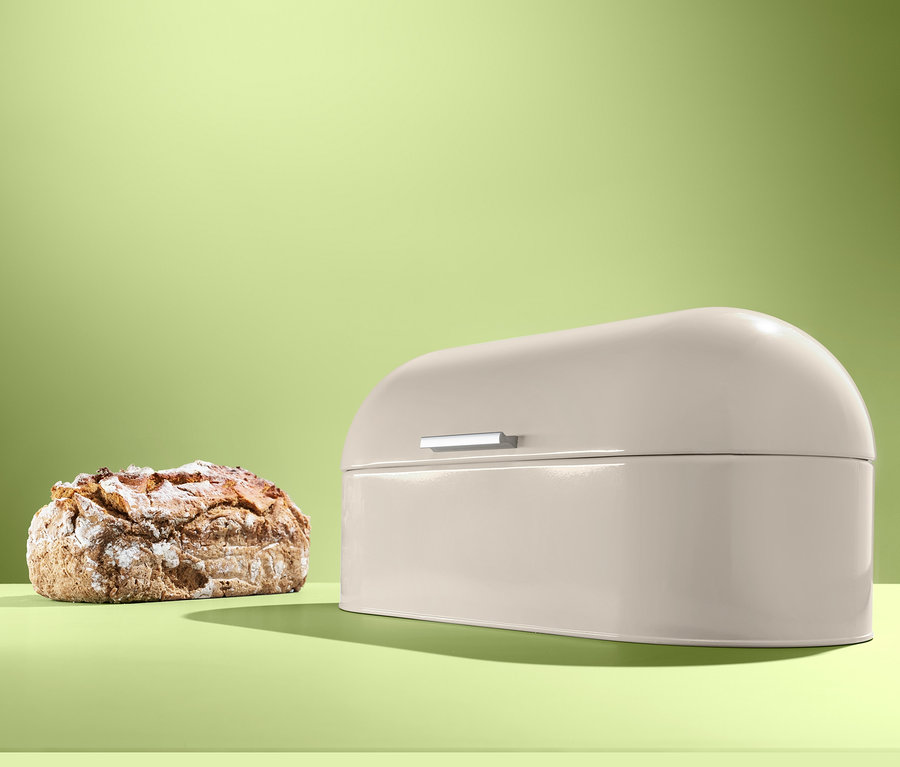 Ein Laib Brot neben einem beigen Brotkasten.