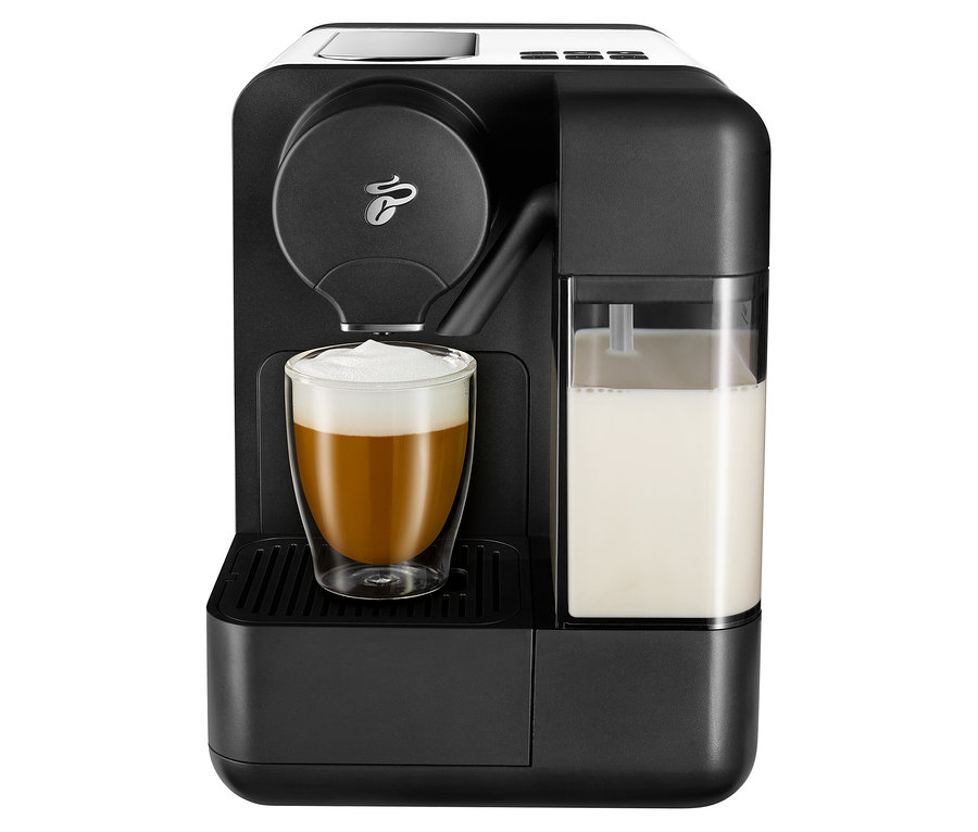 Schwarze Kaffeemaschine mit weißer Cafissimo Milch und einem mit Kaffee gefüllten Glas.