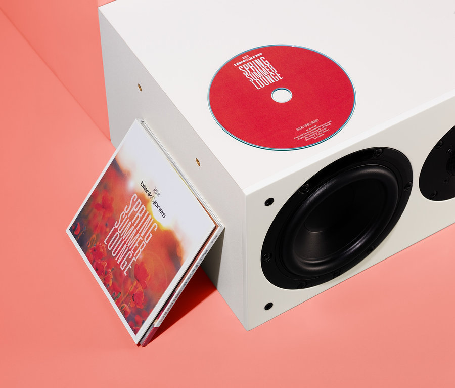 Eine rote CD und die CD-Hülle »Best of Blank & Jones: Spring Summer Lounge« lehnen an einem weißen Lautsprecher.
