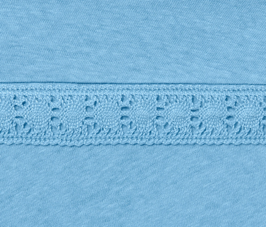 Detailansicht eines hellblauen Leinenmix-Shirts mit dekorativer Spitze.