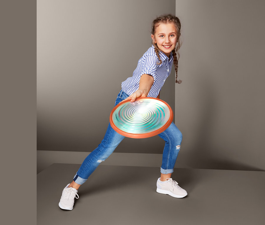 Mädchen wirft LED-Wurfscheibe.