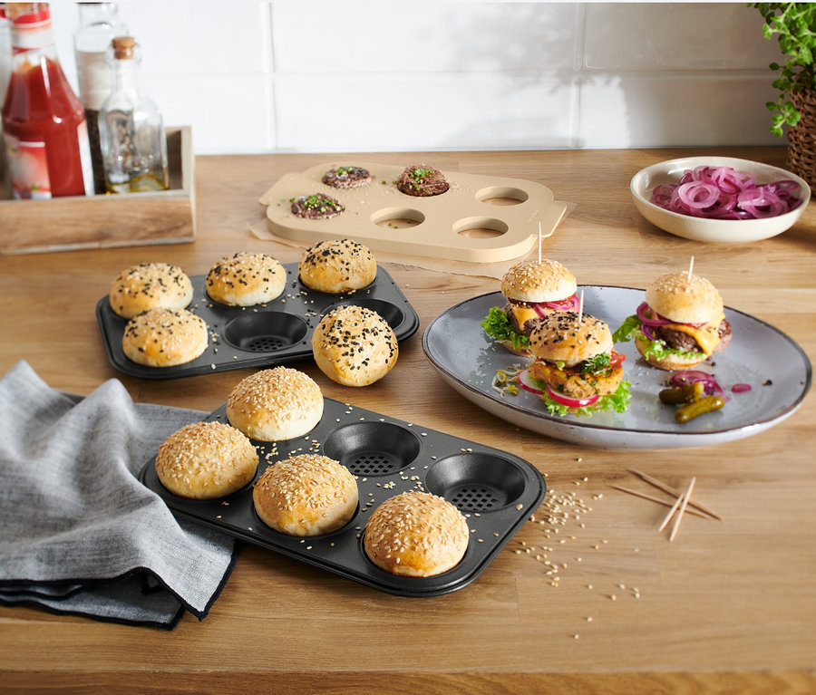 Mini-Burger auf einem Teller und in einem Muffinblech, zusammen mit einem Mini-Burger-Backset.