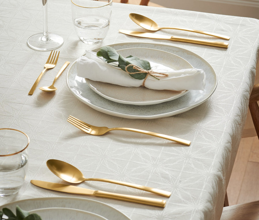 Gedeckter Tisch mit Tellern, Gläsern und goldenem Besteck-Set.