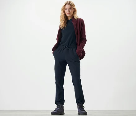 Blonde Frau steht mit Händen in den Taschen der Softshell-Joggpants.