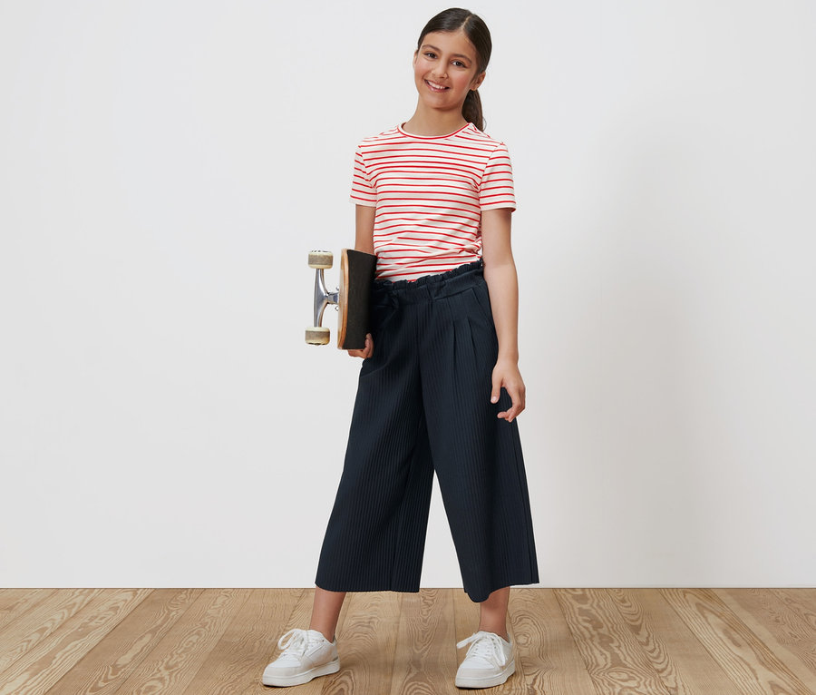 Mädchen hält Skateboard und trägt blaue Kinder-Culotte.