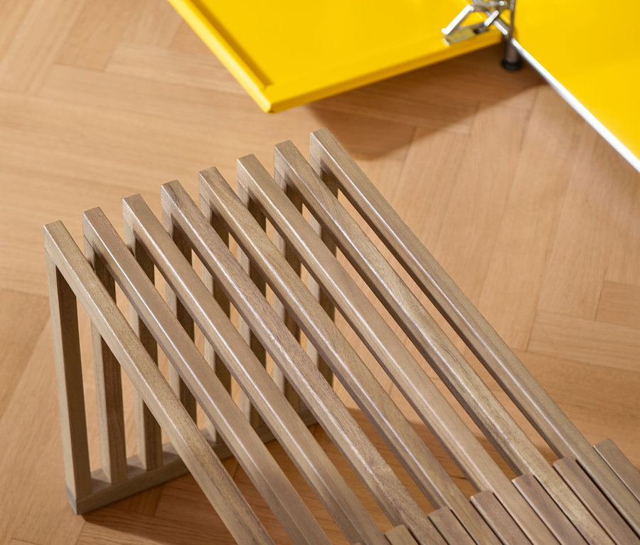 Detailansicht einer Ausziehbank und eines gelben Schranks auf einem Parkettboden.