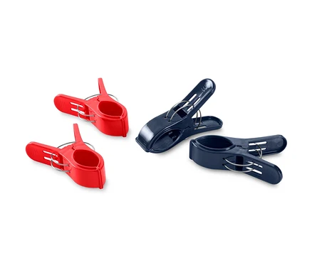 Vier Handtuchclips, zwei rote und zwei dunkelblaue, liegen auf einem weißen Hintergrund.