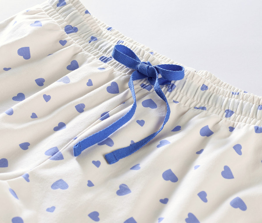 Detailansicht eines Shorty-Pyjamas mit Herzen und blauem Band.