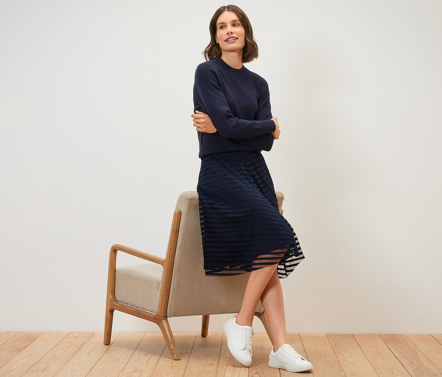 Frau sitzt auf einem Stuhl und trägt einen Mesh-Rock.