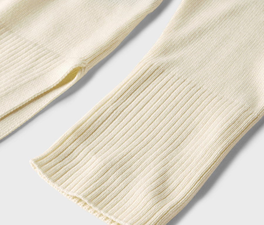 Detailaufnahme eines langen Strickpullovers in Creme.