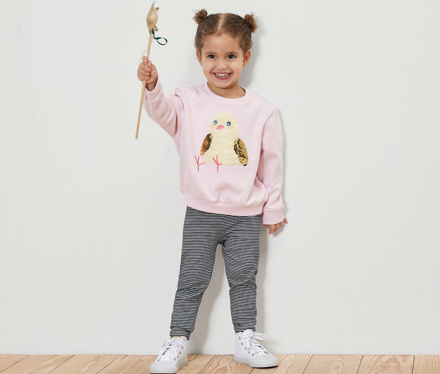 Mädchen hält ein Spielzeugvogel hoch und trägt 5 Kinder-Leggings.