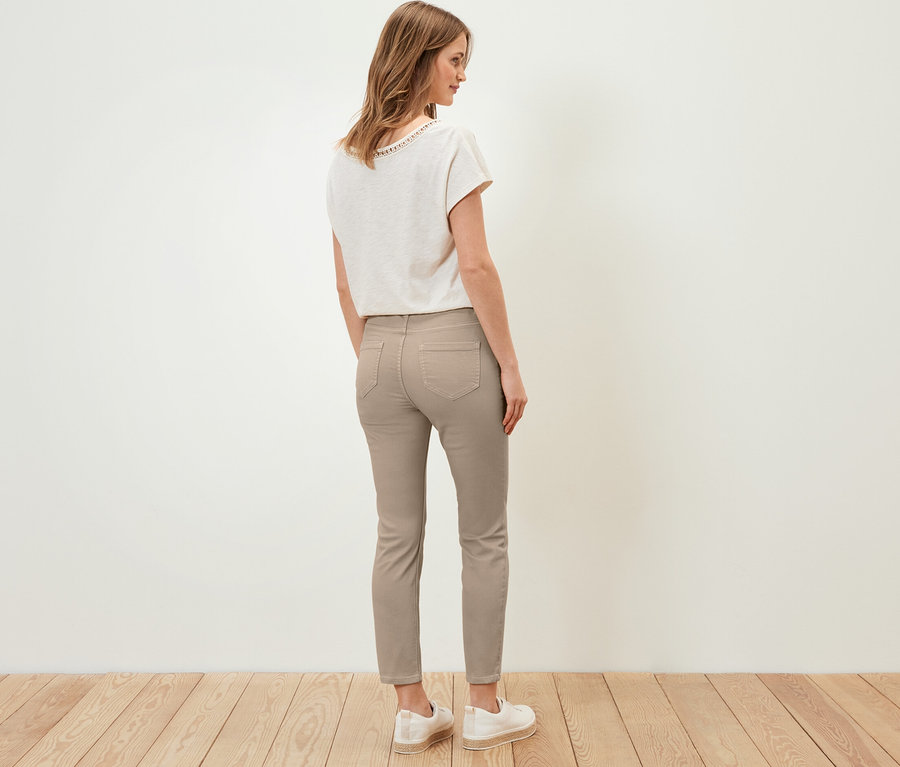 Eine Frau steht mit dem Rücken zur Kamera und trägt 7/8-Treggings, ein T-Shirt und Schuhe.