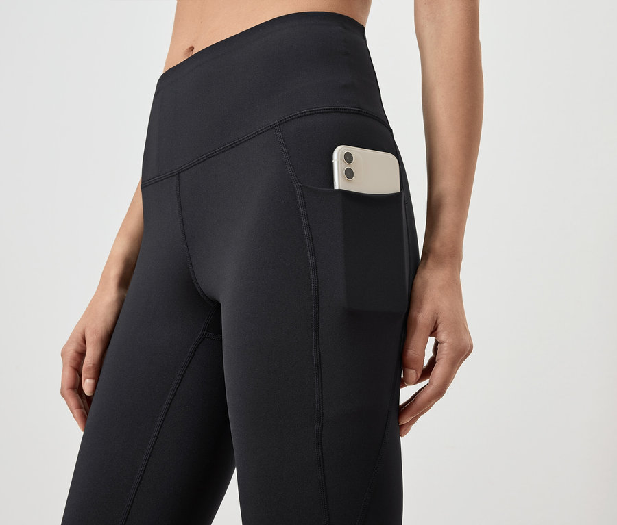 Detailaufnahme von schwarzen Damen Leggings mit Tasche und Handy.