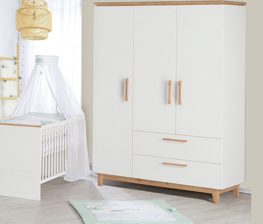 Ein Kinderzimmer mit einem weißen Kinderbett mit Himmel, einem weißen dreitürigen Kleiderschrank und einer Spieldecke auf dem Boden.