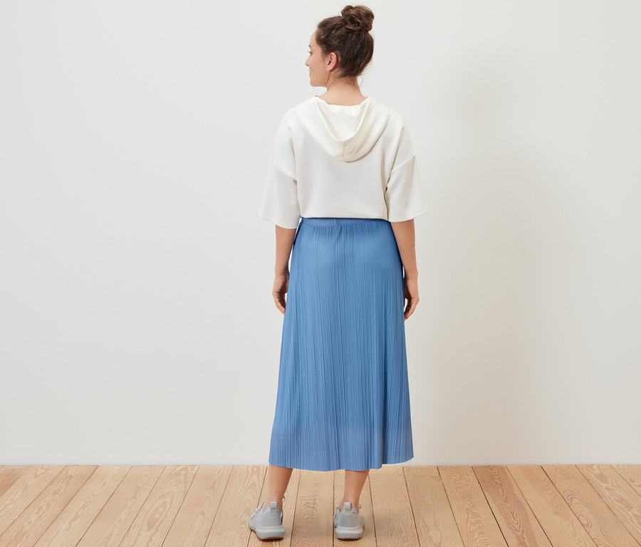 Frau trägt einen Plisseerock.